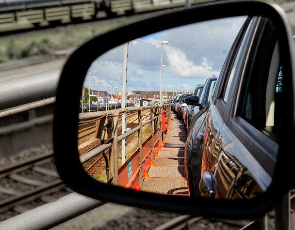 View through the rearview mirror of cars on the upper deck of a car train