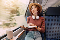 Happy young girl rides in a modern intercity train and remotely via Wi Fi Internet works or studies or watches a movie